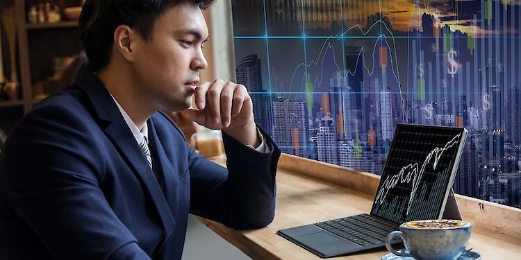 Man kijkt naar laptop met koffie naast hem, met een digitaal scherm op de achtergrond