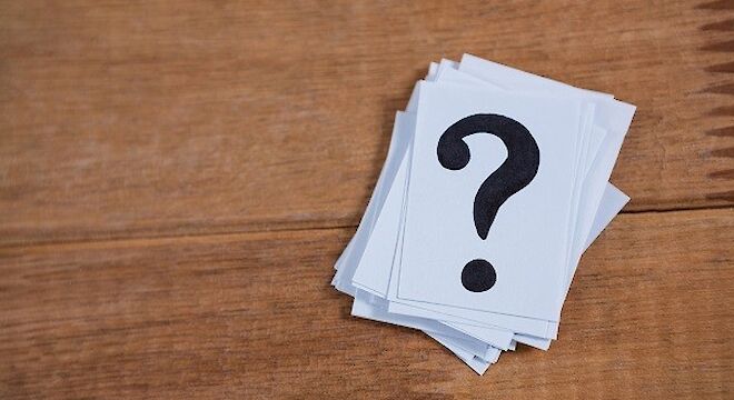 stapel papiertjes, op bovensta staat een zwarte vraagteken