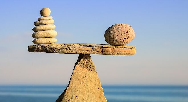 Stenen die balanceren op een driehoekige steen. Met de zee op de achtergrond