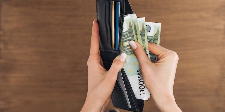 Bovenaanzicht van een vrouw die 100 eurobiljetten in portemonnee doet