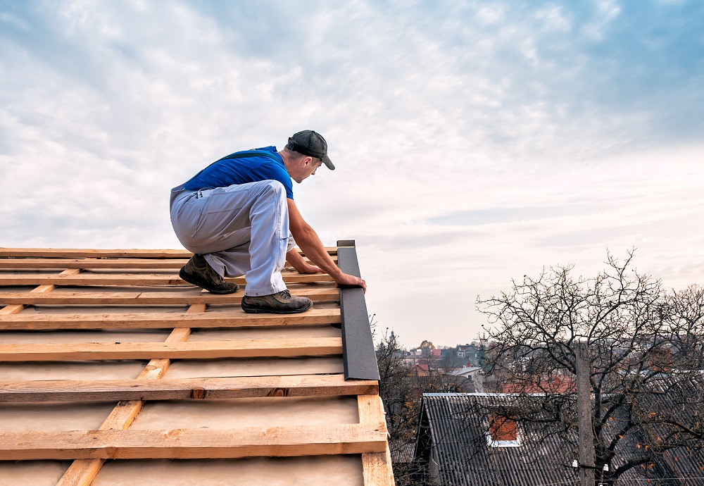 Man op dak bezig met reparatie dak