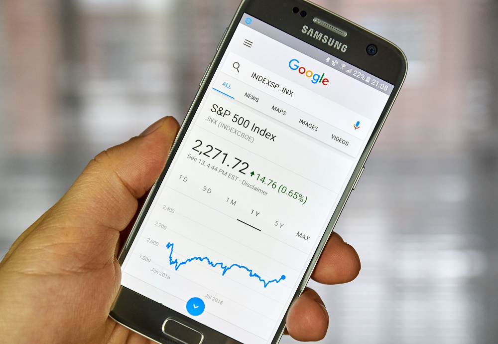 Hand met telefoon met de index van de S&P 500 open.