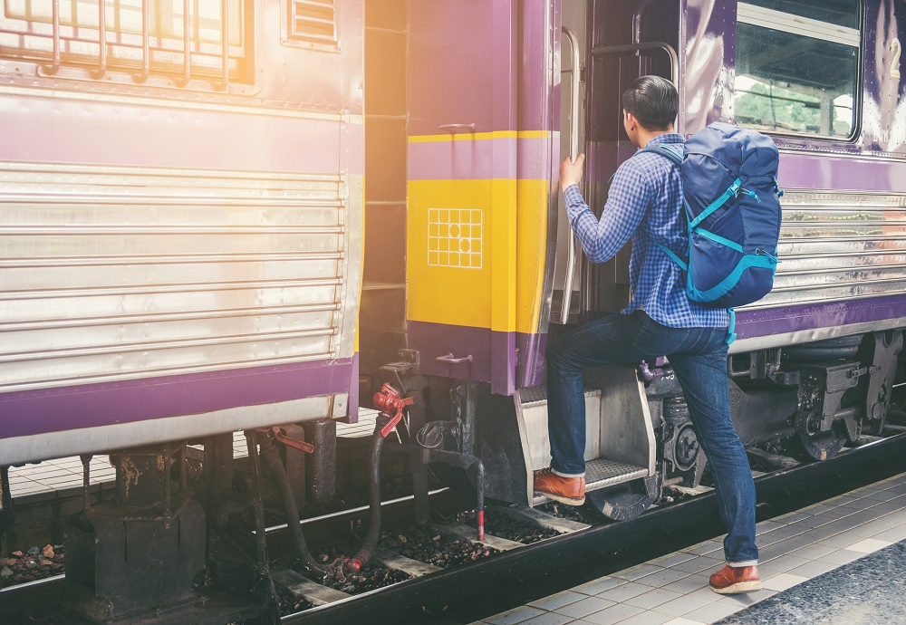 Man met rugzak die in de trein stapt.