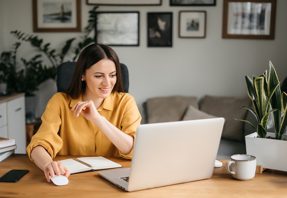 Vrouw thuis lacht naar laptop.